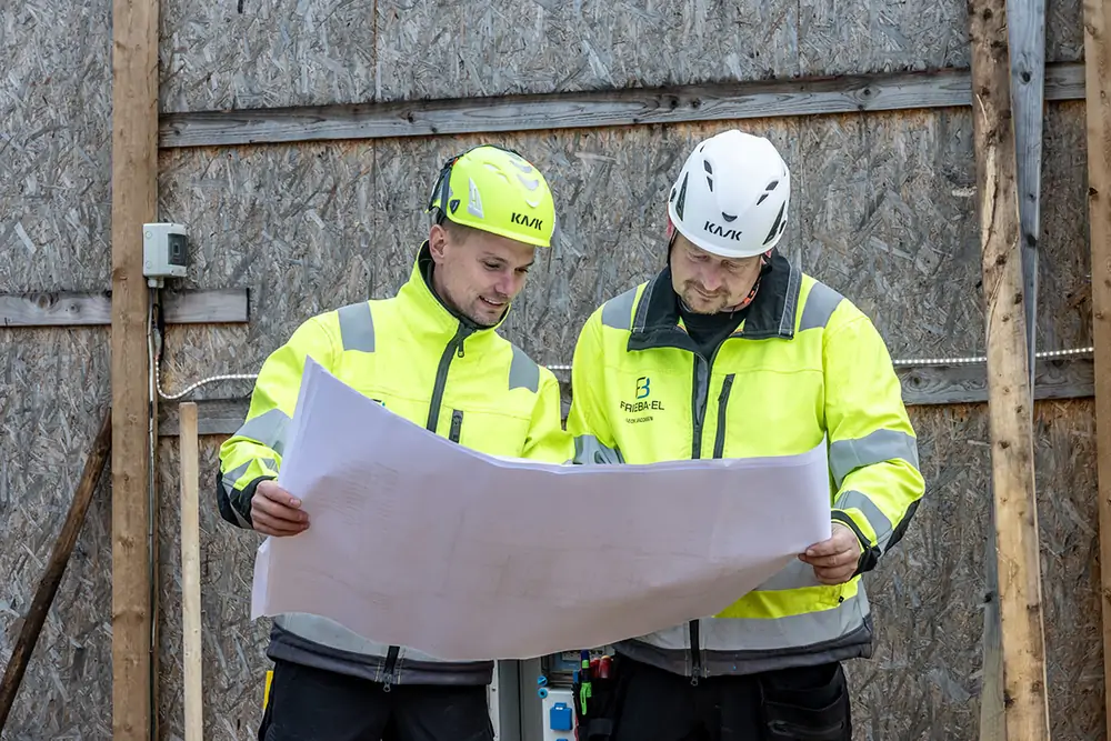 To elektrikere fra Frieba-el gennemgår tegninger på byggepladsen